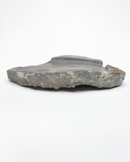 Side: organic-shaped gray stone tray with raw edges, brown and white flecks, subtle veining.
