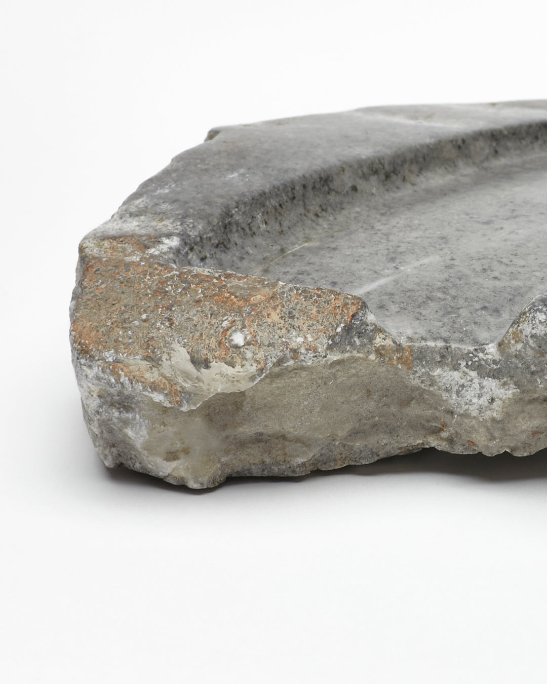 Angled close-up: organic-shaped gray stone tray with raw edges, flecks, subtle veining.