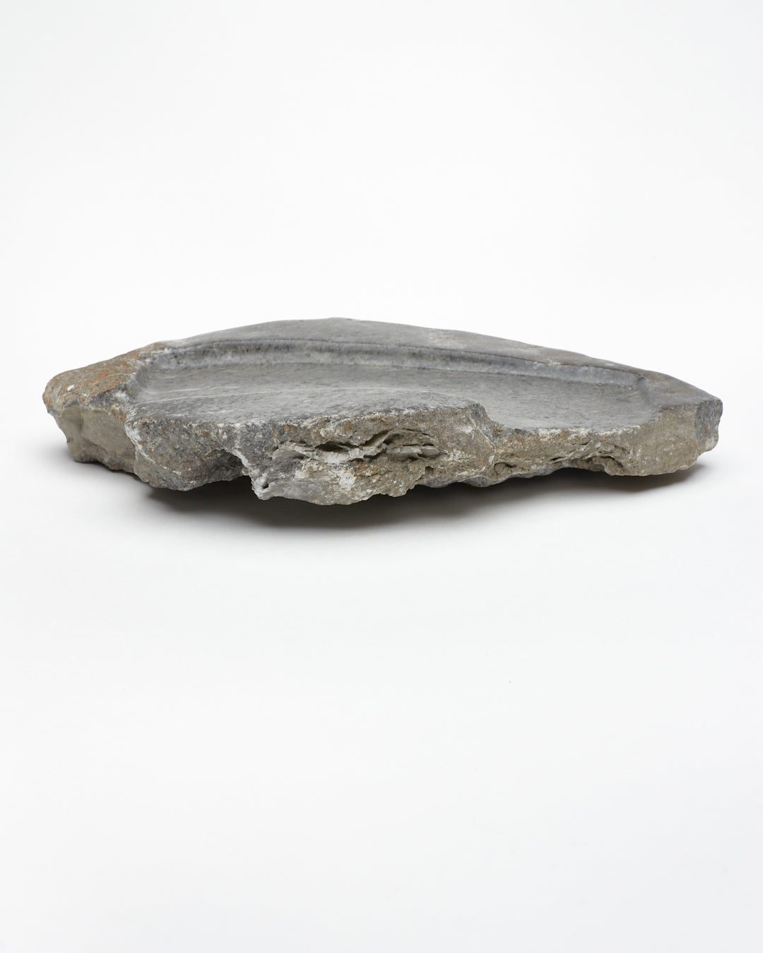 Side view: organic-shaped gray stone tray with raw edges, brown and white flecks.