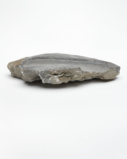 Side view: organic-shaped gray stone tray with raw edges, brown and white flecks.