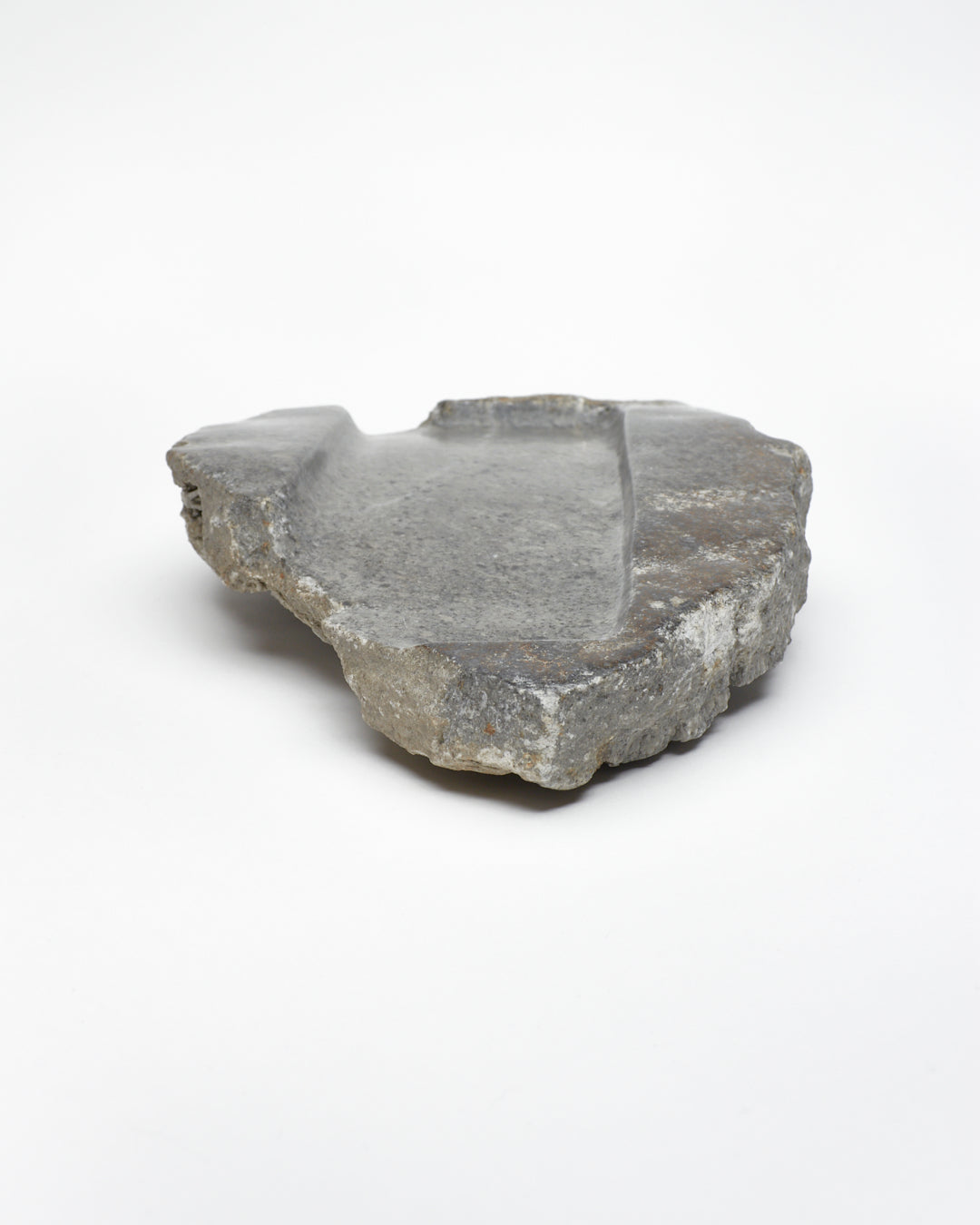 Front-on: organic-shaped gray stone tray with raw edges, brown and white flecks.