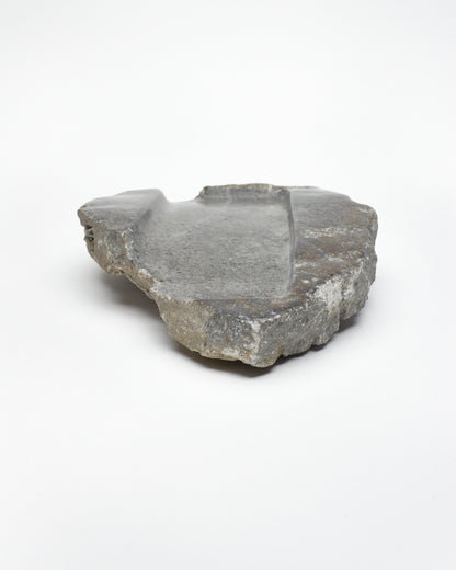 Front-on: organic-shaped gray stone tray with raw edges, brown and white flecks.