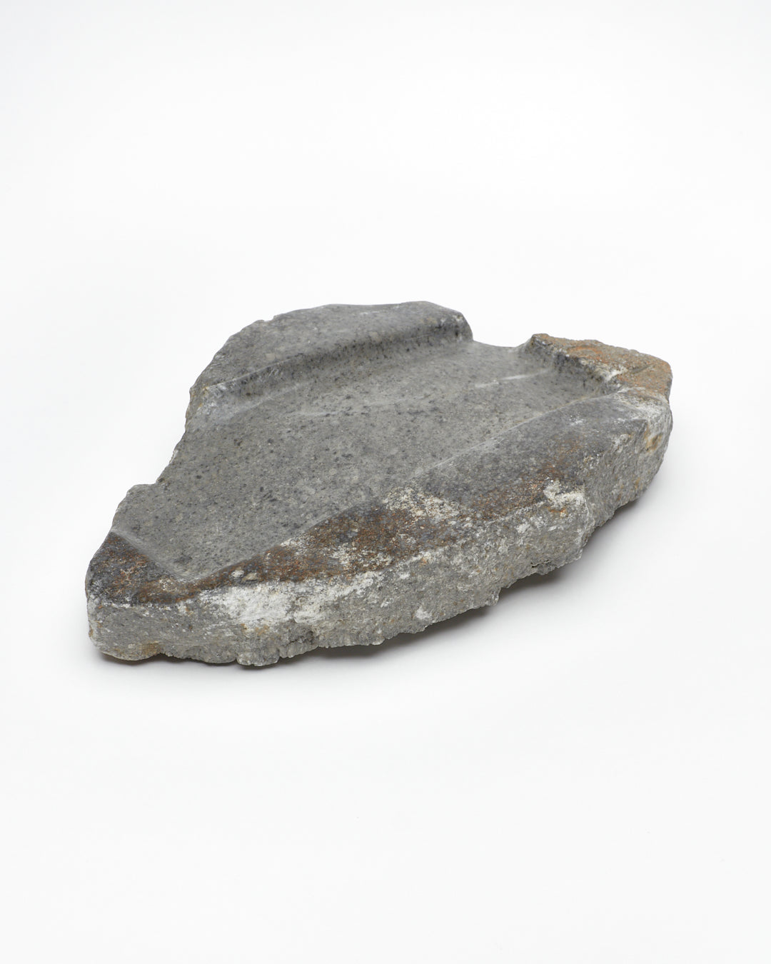 Angled: Organic-shaped gray stone tray with raw edges, brown and white flecks, subtle veining.