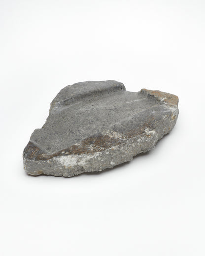 Angled: Organic-shaped gray stone tray with raw edges, brown and white flecks, subtle veining.