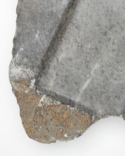 Top-down close-up: organic-shaped gray stone tray with brown and white flecks, subtle veining.