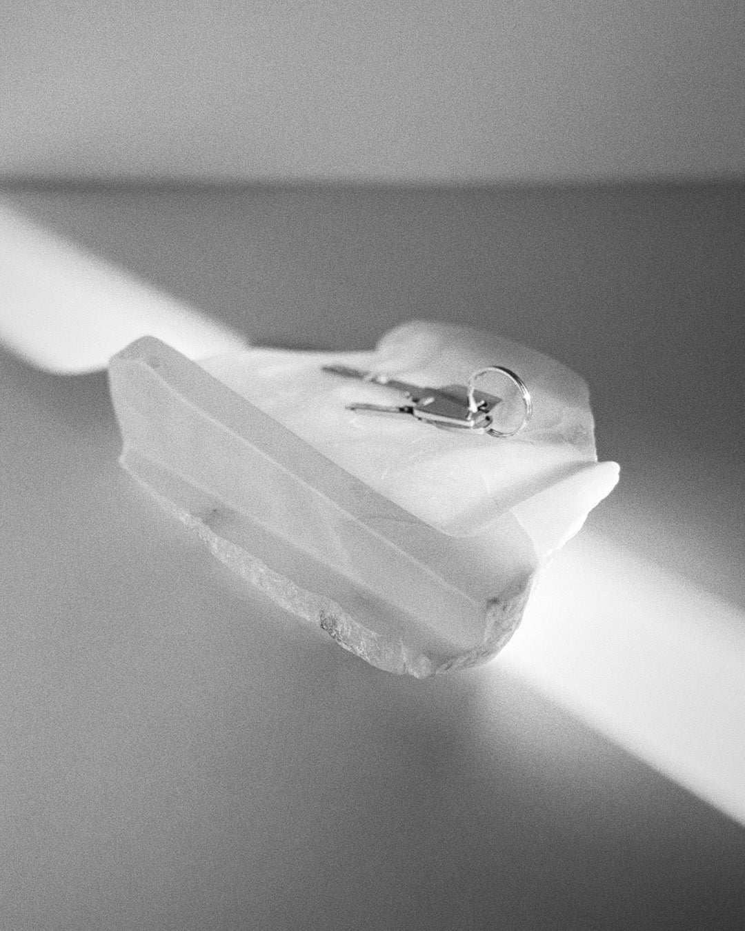 Angled view: white translucent alabaster tray, raw and smooth edges, holding keys.