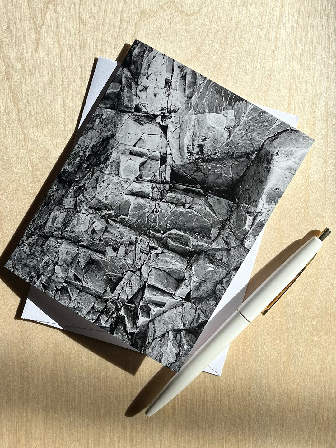 Greeting card with black and white close up print of textured rocks, with envelope and pen.