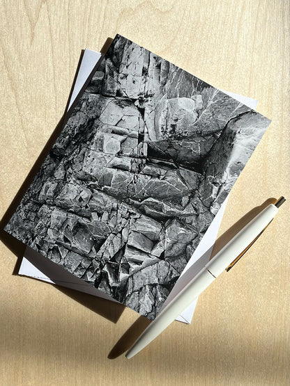 Greeting card with black and white close up print of textured rocks, with envelope and pen.