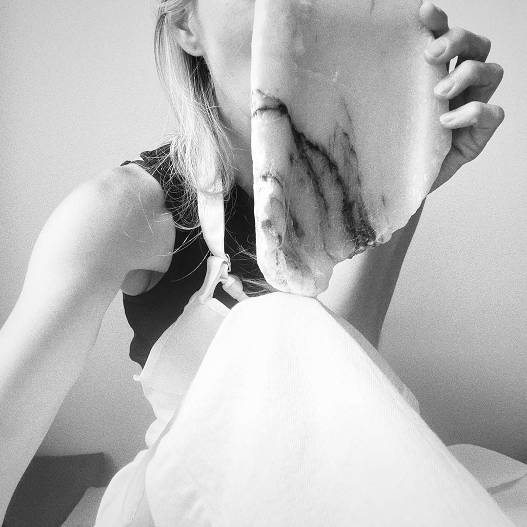 Woman holding a stone tray over her face.